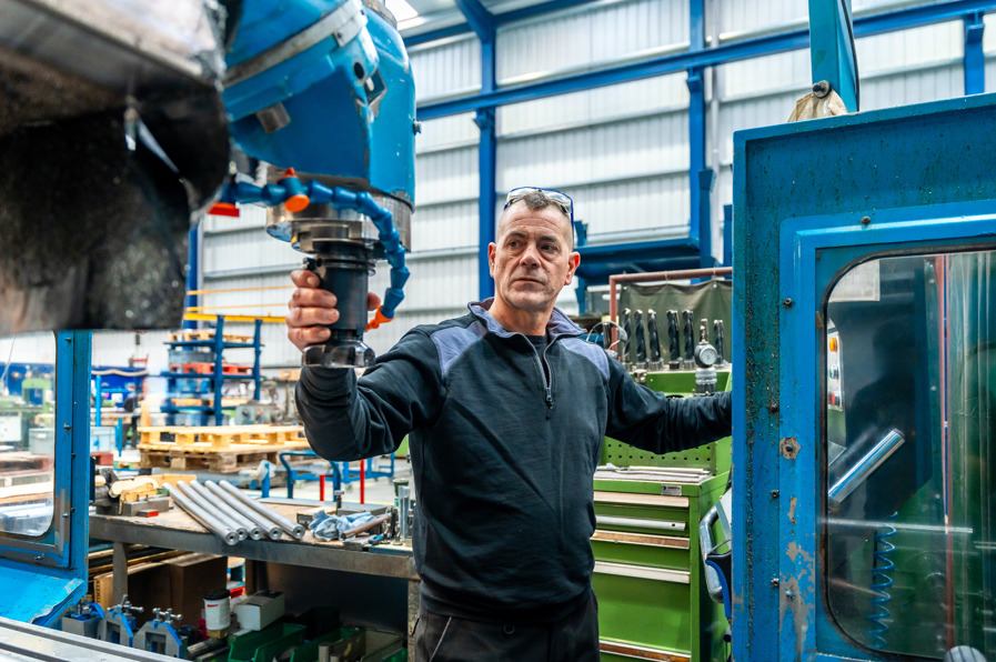 Technician inspecting industrial machinery used for rotary torque sensor testing and rotary motion measurement.